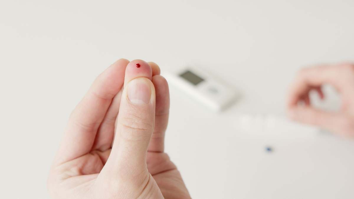 A close-up of a fingertip blood sample being taken for a rapid test