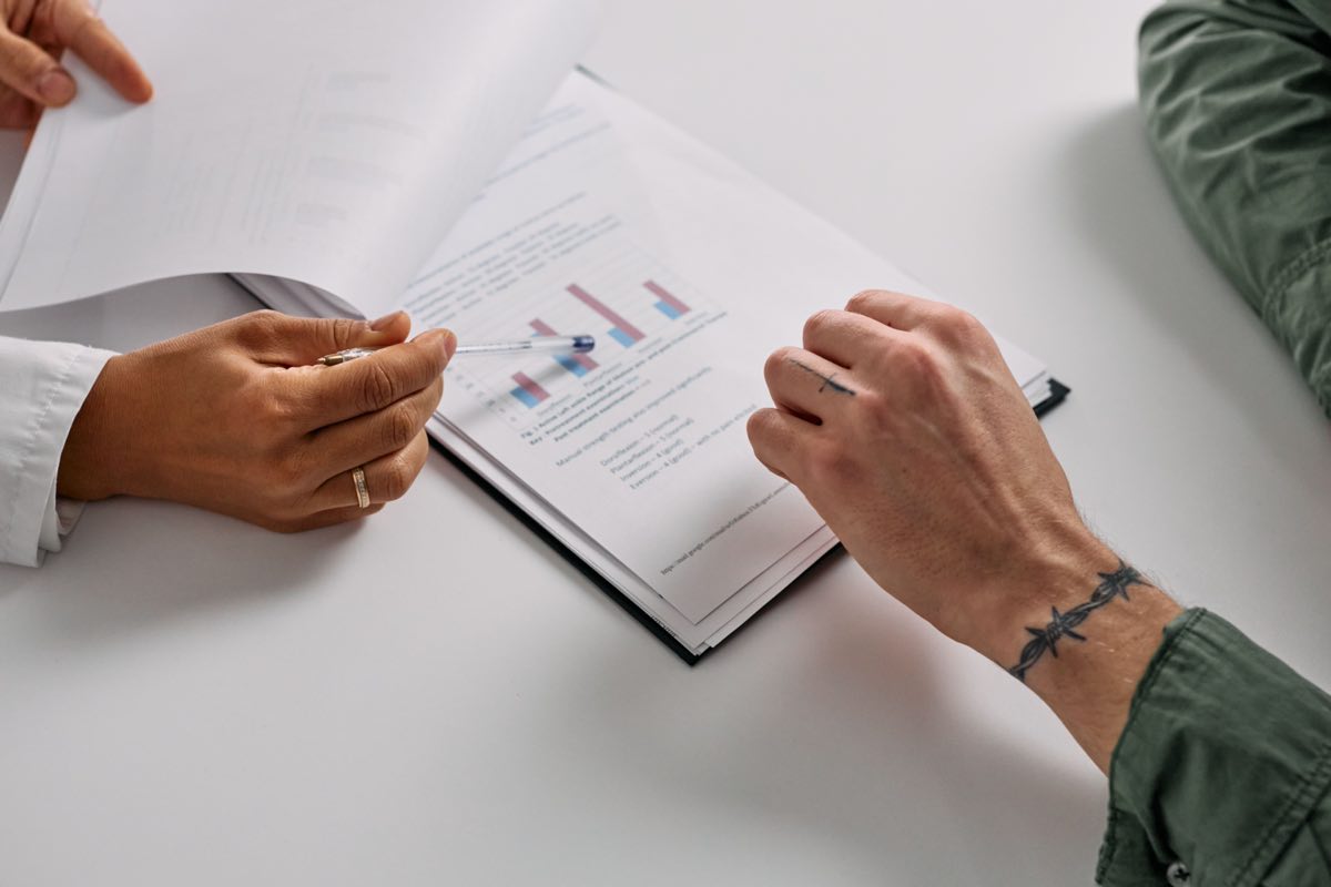 Hands reviewing documents with graphs at a table