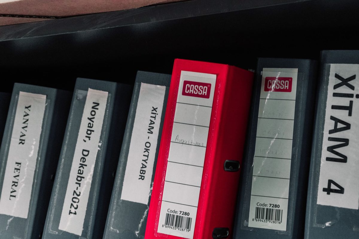 Color-coded, labeled binders organized on a storage shelf