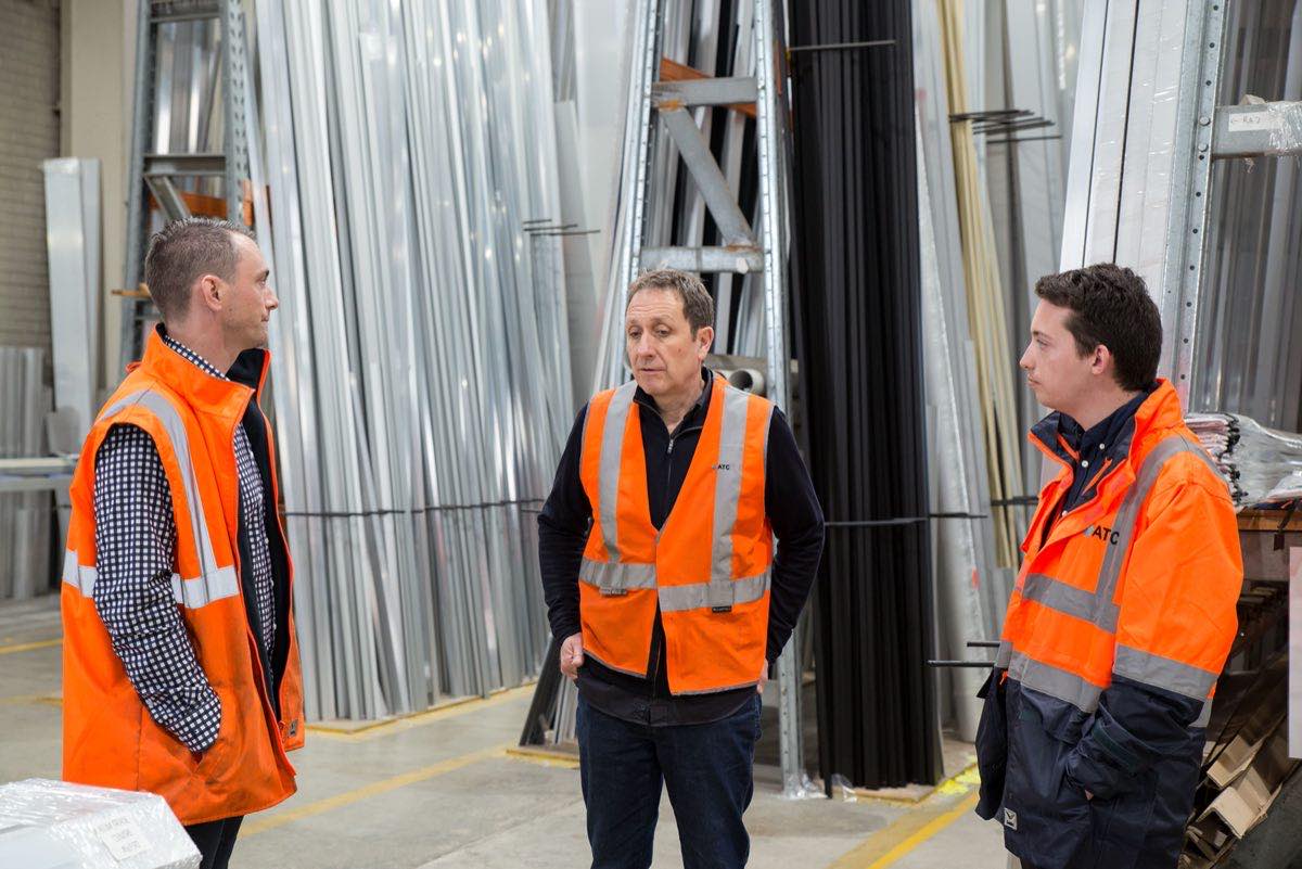 A team in high-visibility vests in discussion on a warehouse floor