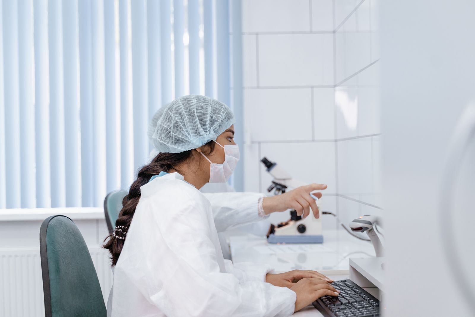 A gowned quality professional reviewing records at a workstation inside a controlled laboratory
