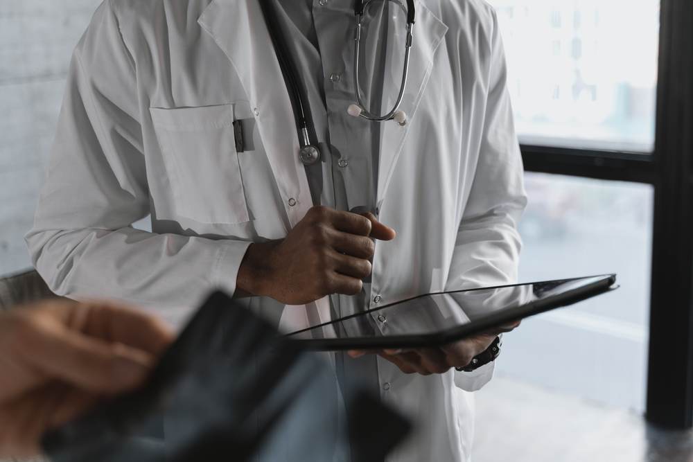 A medical practitioner holding a tablet in consultation
