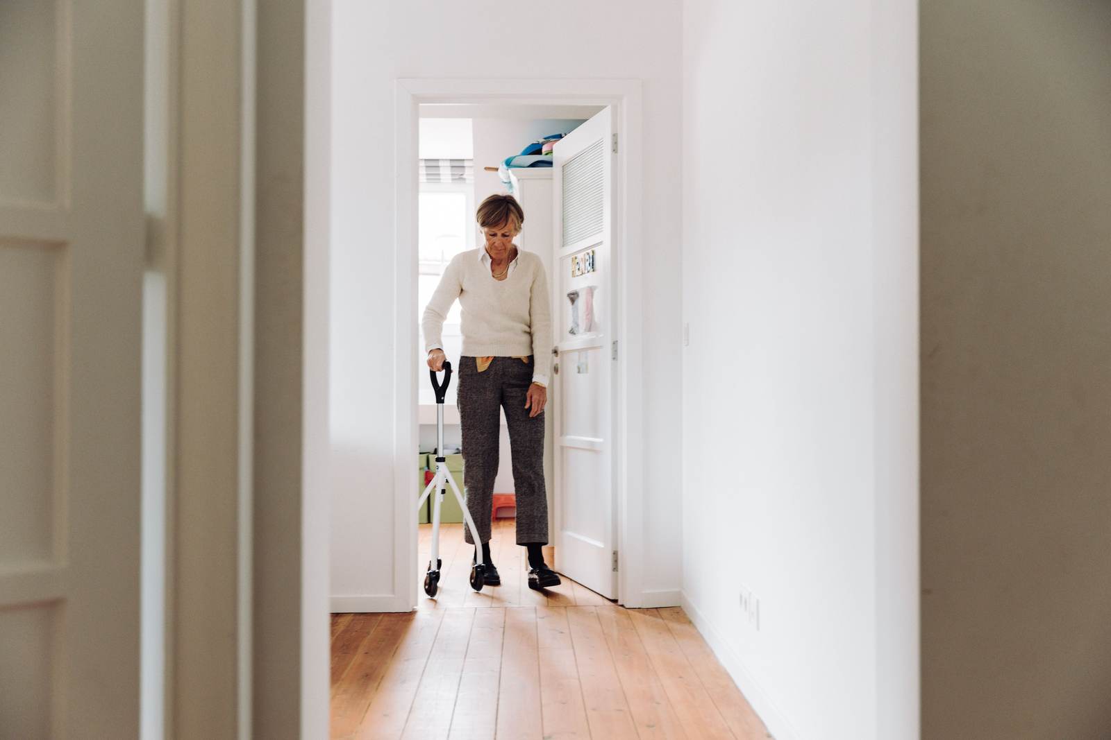 A person walking with support in a brightly lit hallway
