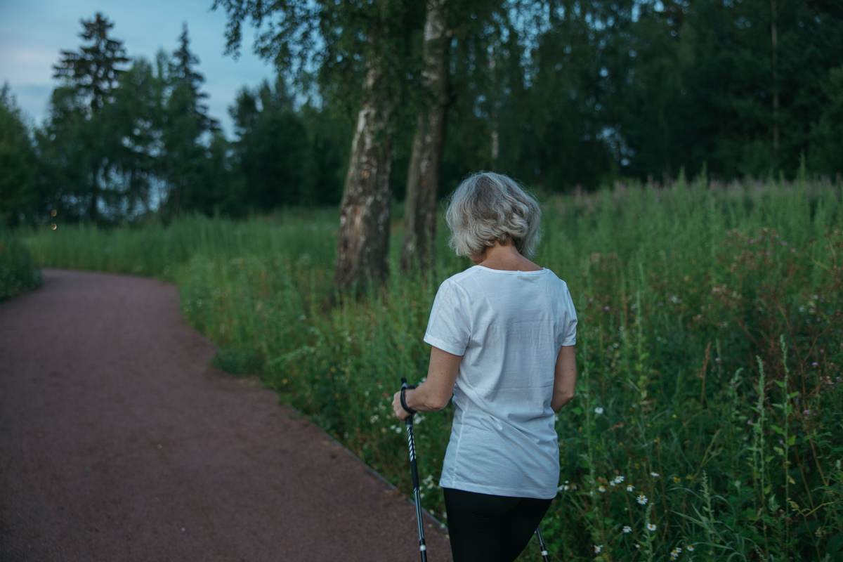 An older adult practicing walking on a park trail