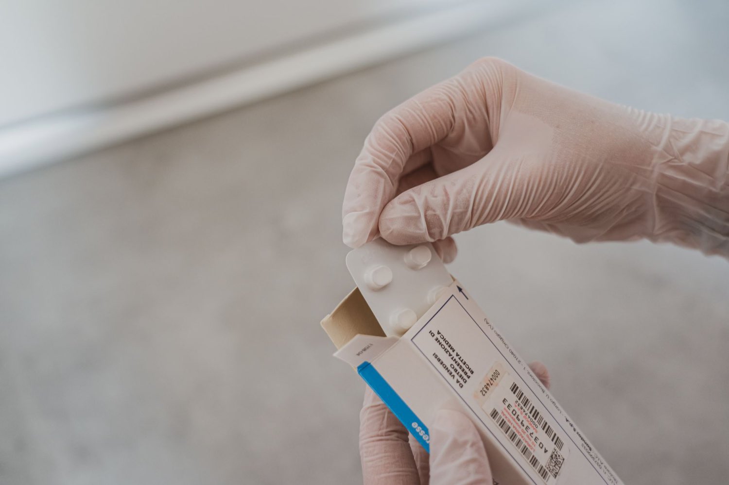 A gloved hand handling a medicine carton and its labeling