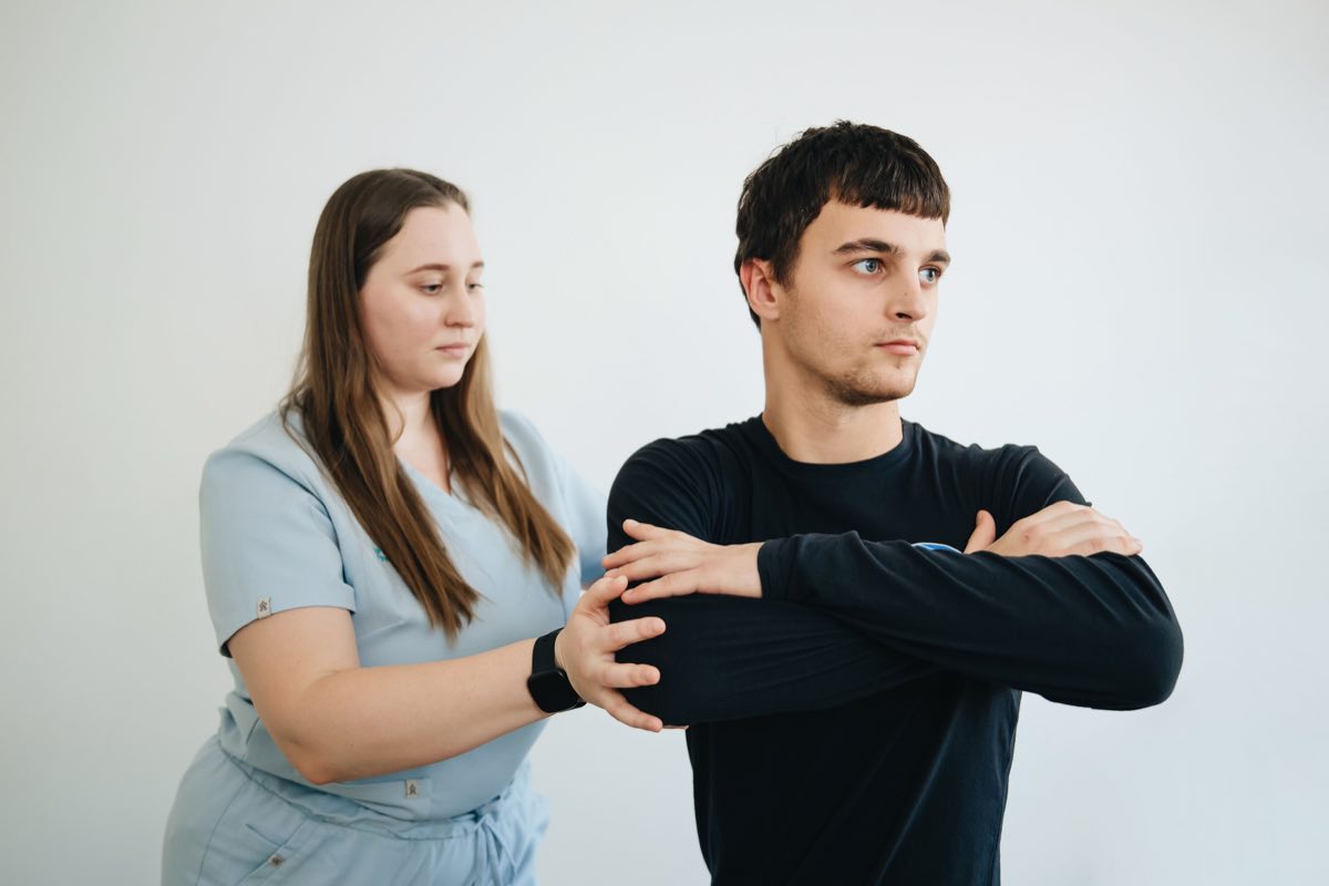 A physiotherapist assists a patient with arm exercises in a clinical setting