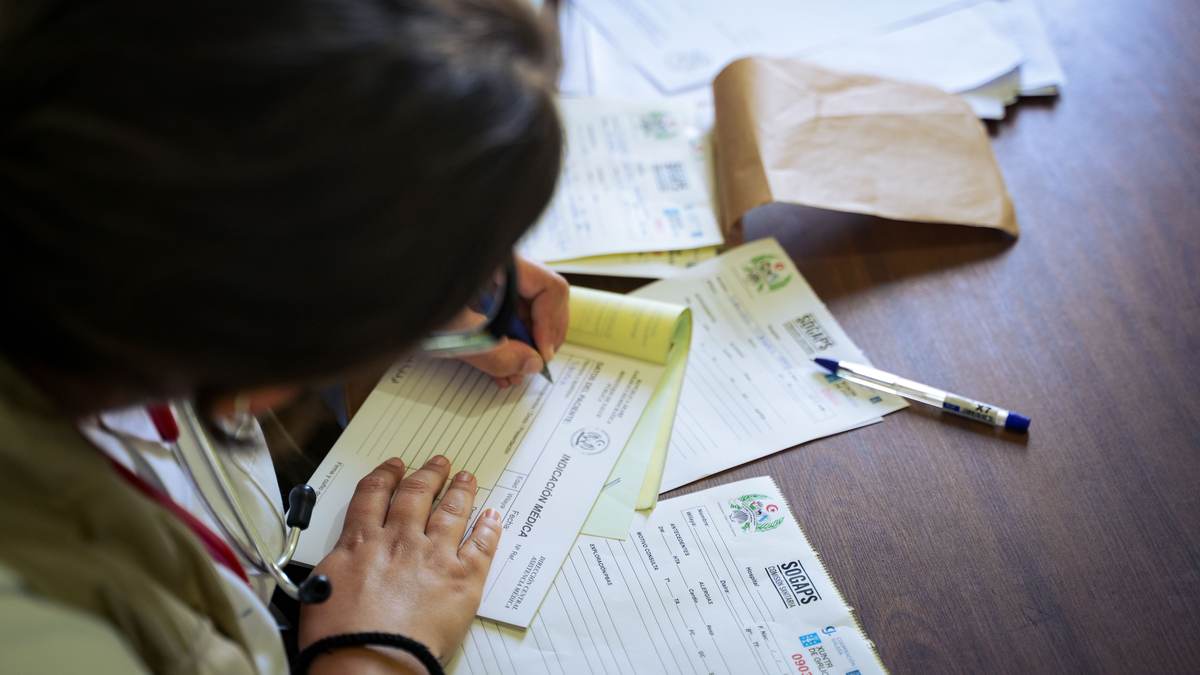 A doctor filling out medical forms at a desk