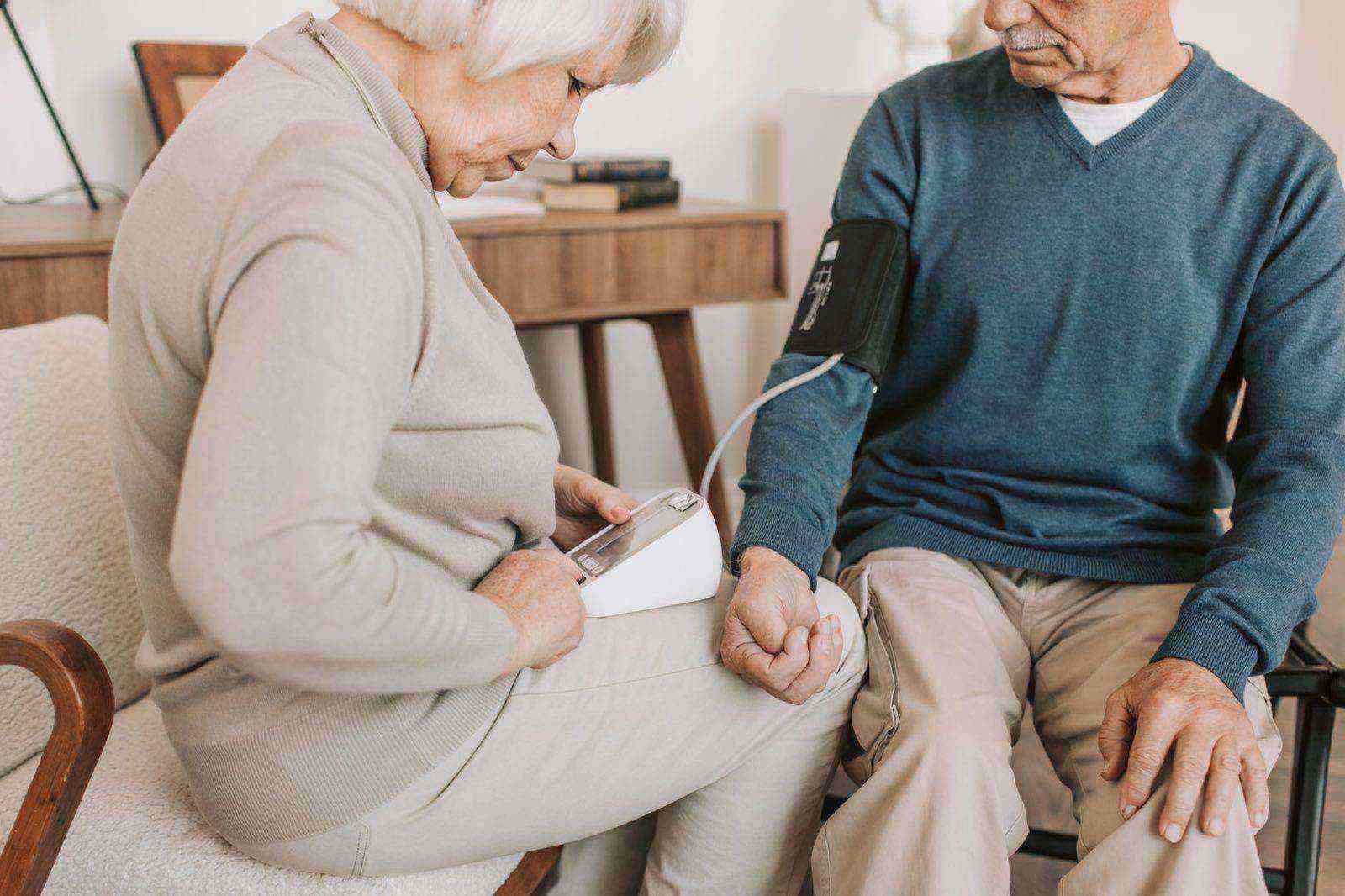 A senior couple at home measuring blood pressure together