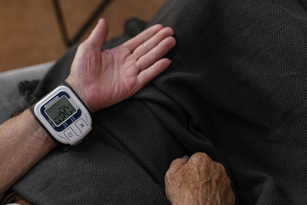 A senior adult using a wrist blood pressure monitor at home