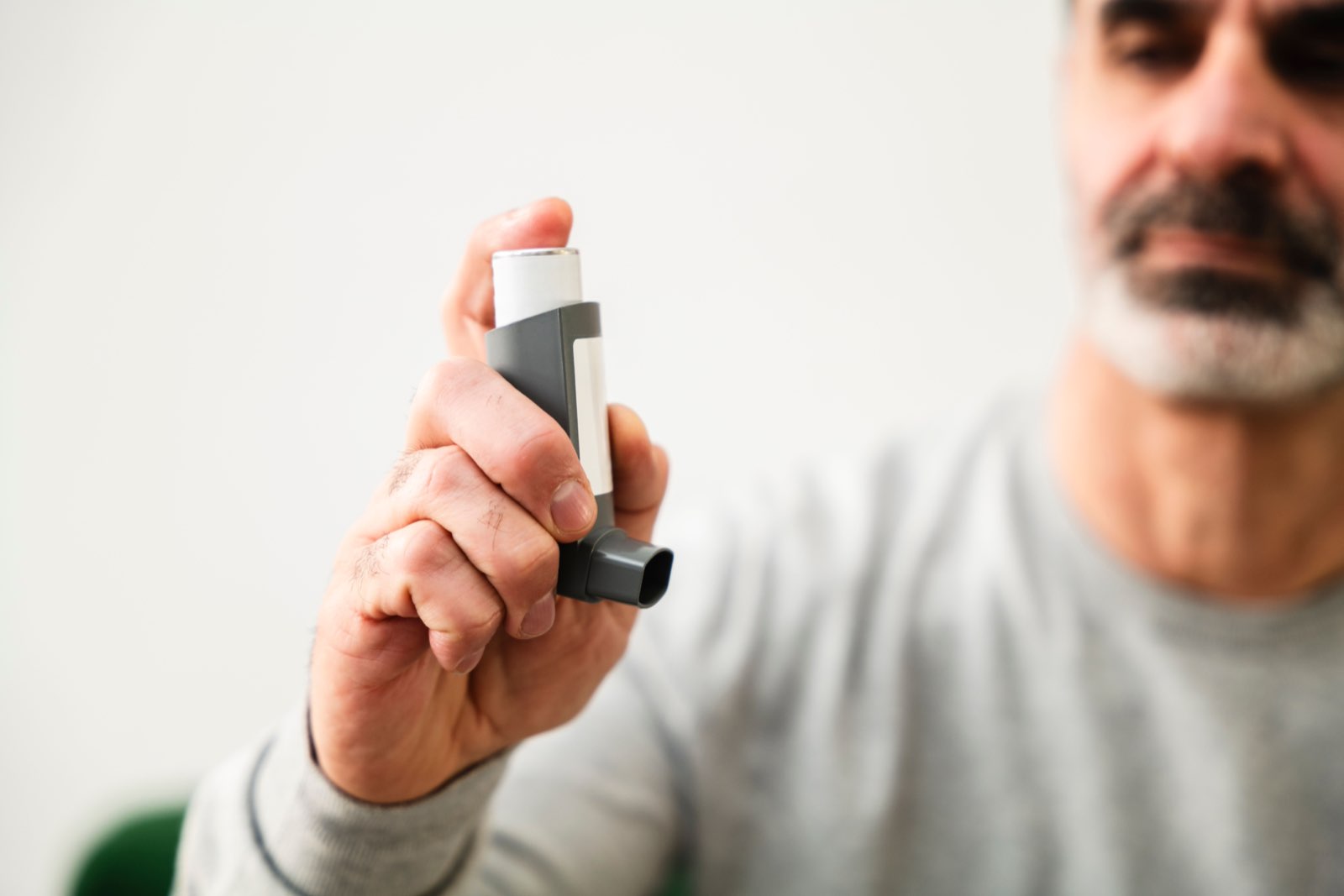 A patient using an inhaler to manage a respiratory condition