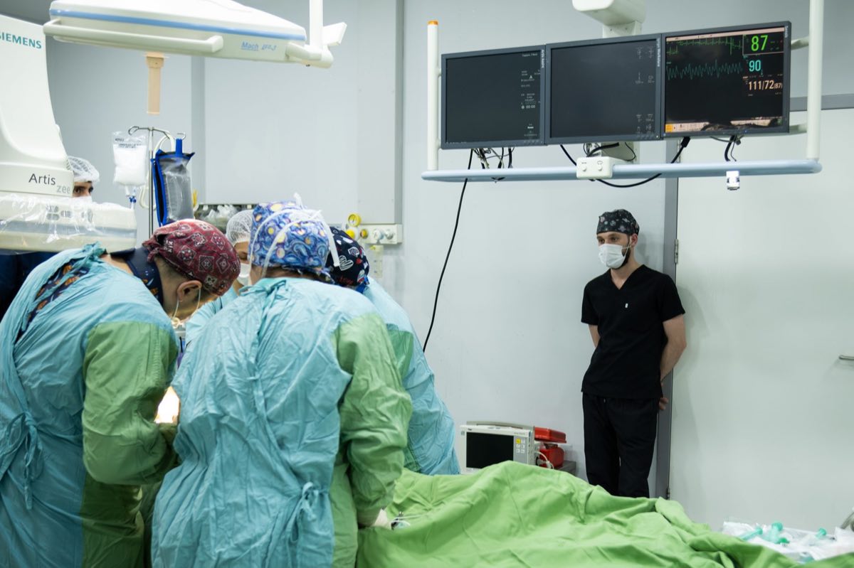 A surgical team in an operating room watching data on wall-mounted monitors