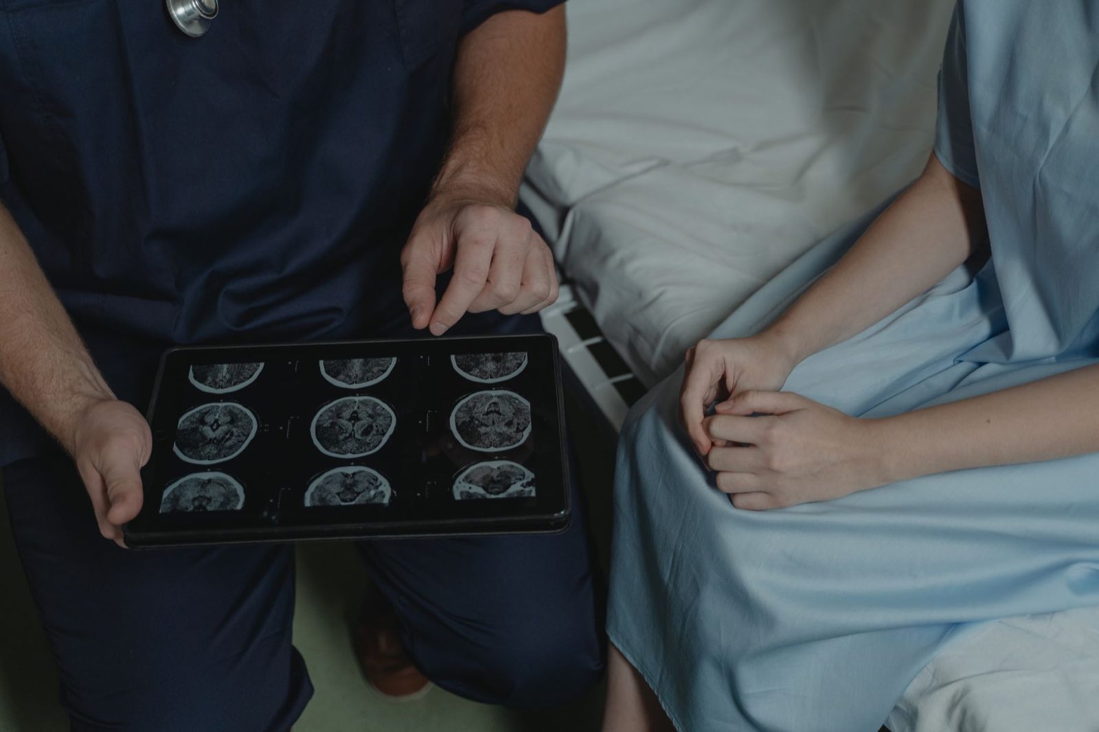 A doctor explains brain scan images on a tablet to a patient