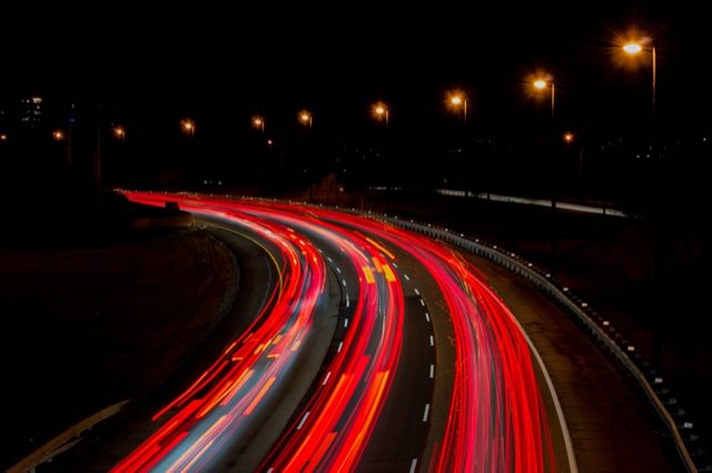 Red light trails of night traffic streaming down a highway