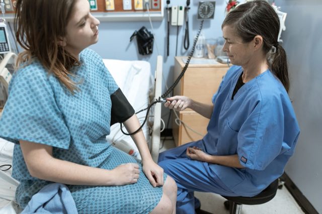Research nurse taking a patient's blood pressure at a clinic visit