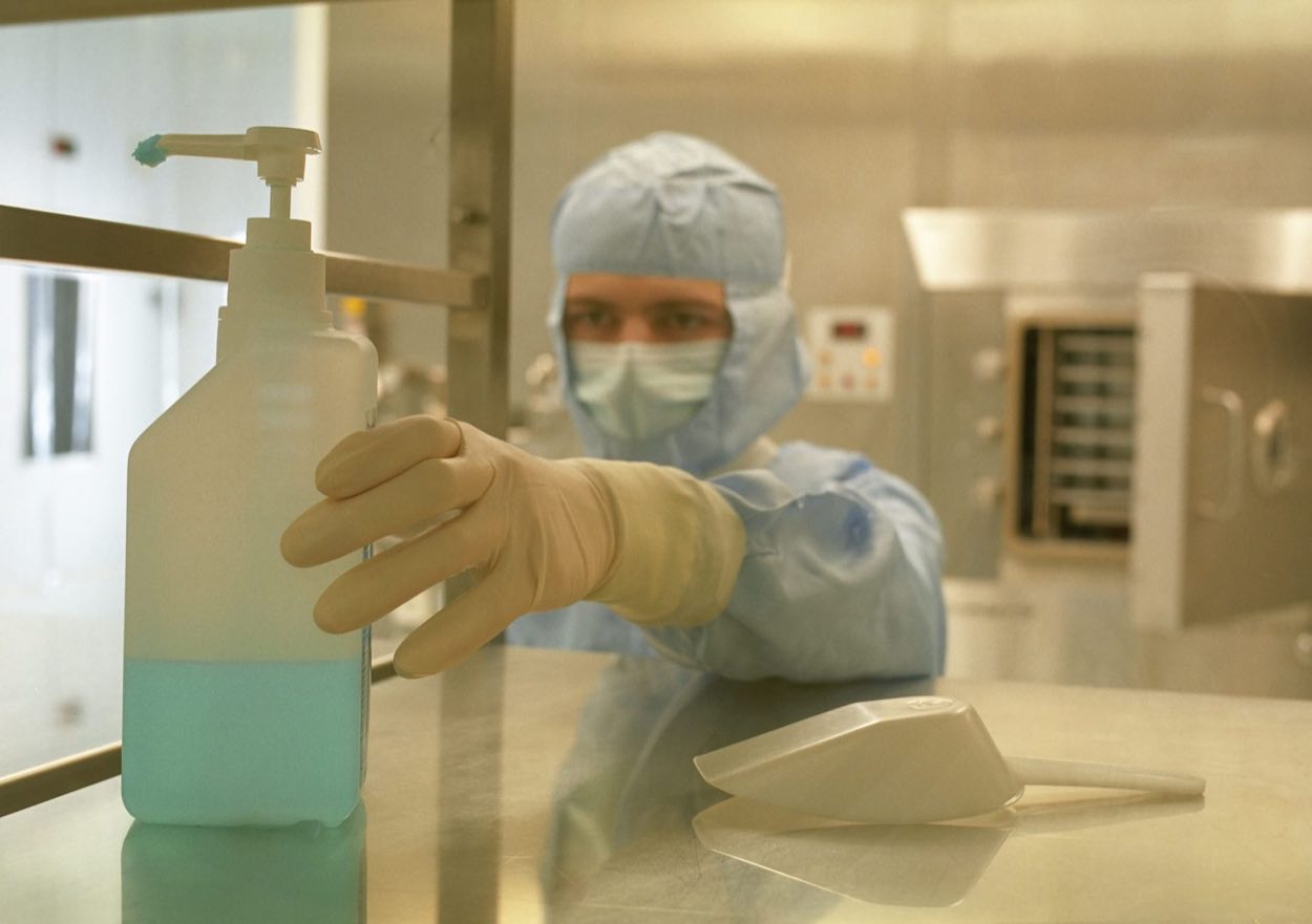 Gowned technician at work inside a pharmaceutical cleanroom