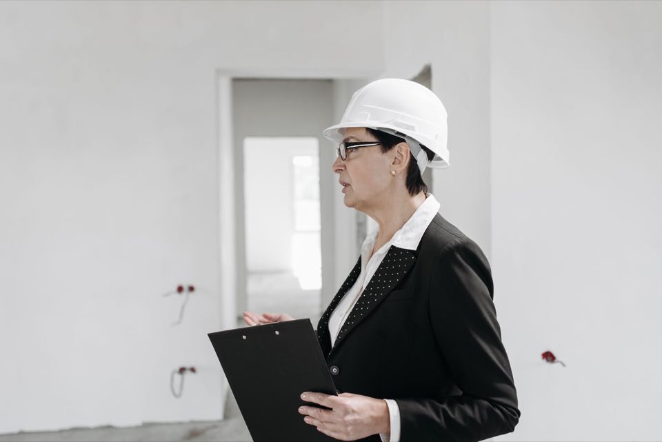 Inspector in a hard hat walking a facility with a checklist