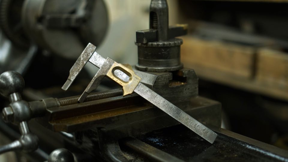 Precision caliper measuring a machined metal part