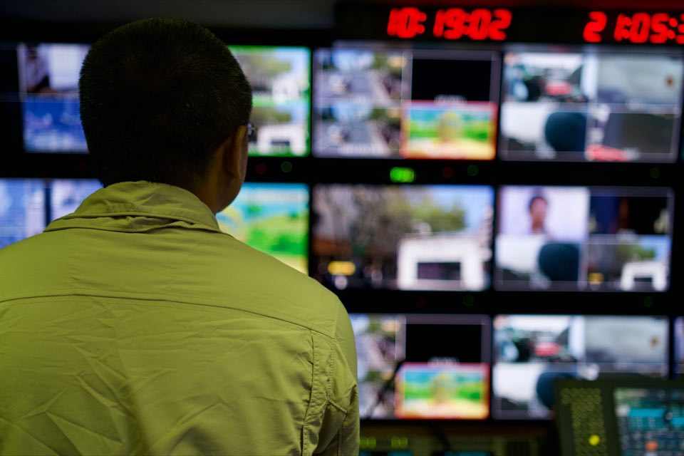 Analyst overseeing a wall of live data monitors in a control room
