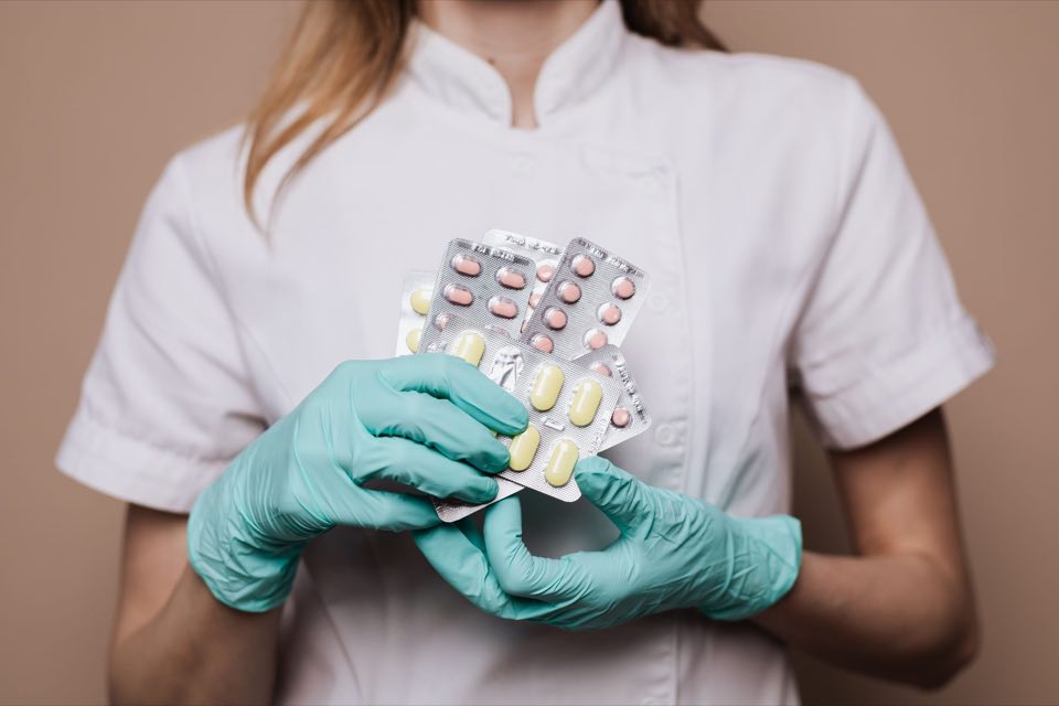 Gloved pharmacist holding blister-packed medication