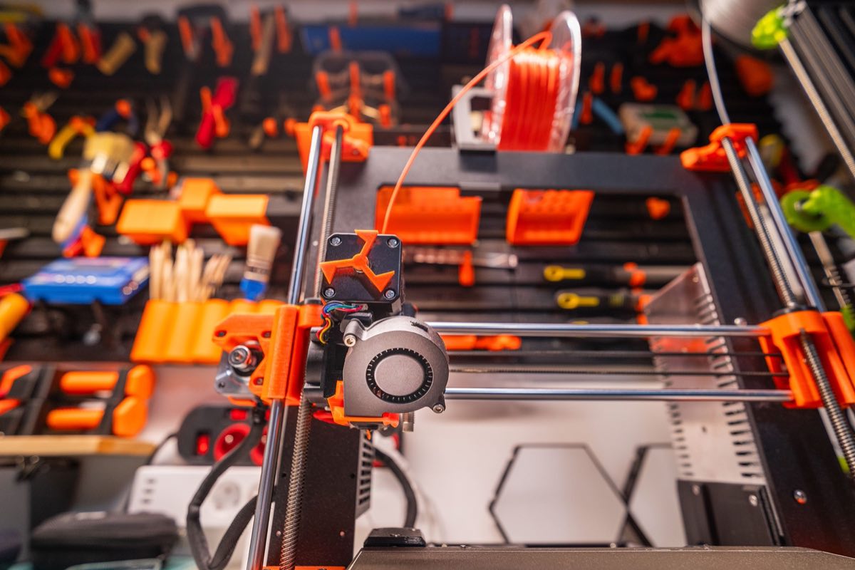 A workshop bench with a 3D printer and prototyping tools
