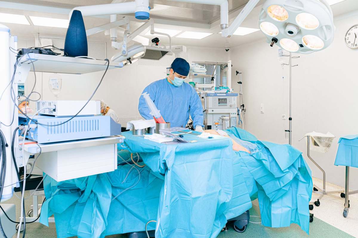 A clinician in surgical attire working in a well-equipped operating room