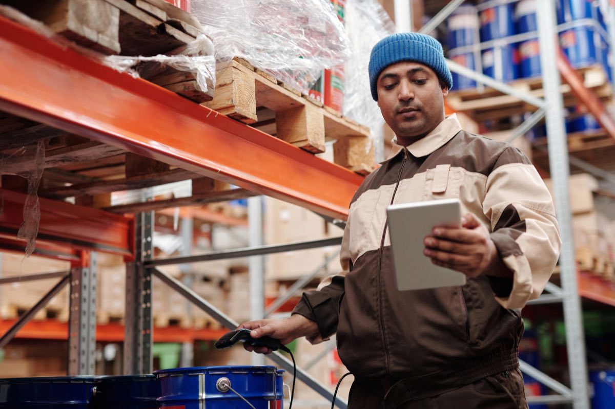 A warehouse employee verifying inventory with a tablet and scanner