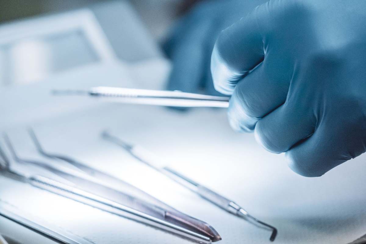 A close-up of a surgeon's gloved hand holding a surgical instrument
