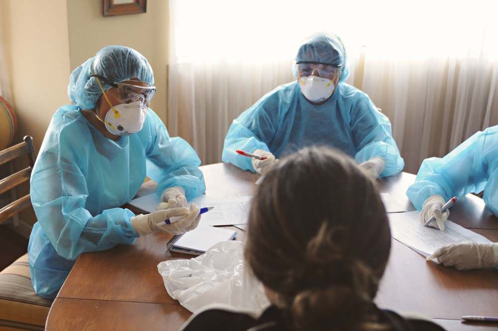 Healthcare professionals in protective equipment discussing a procedure