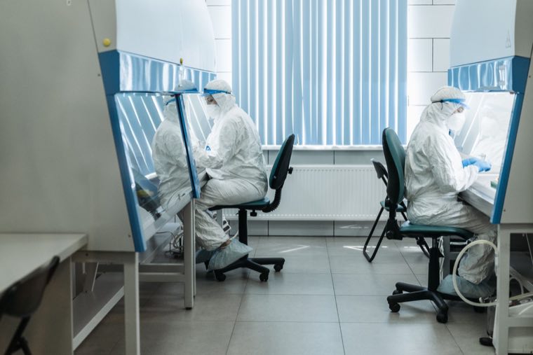 Scientists in full protective gowning inside a biologics cleanroom