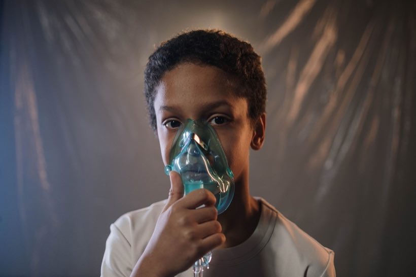 Portrait of a child using an oxygen mask indoors, highlighting health care needs