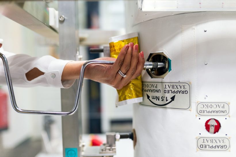 Gloved hand loading a sample into stainless processing equipment