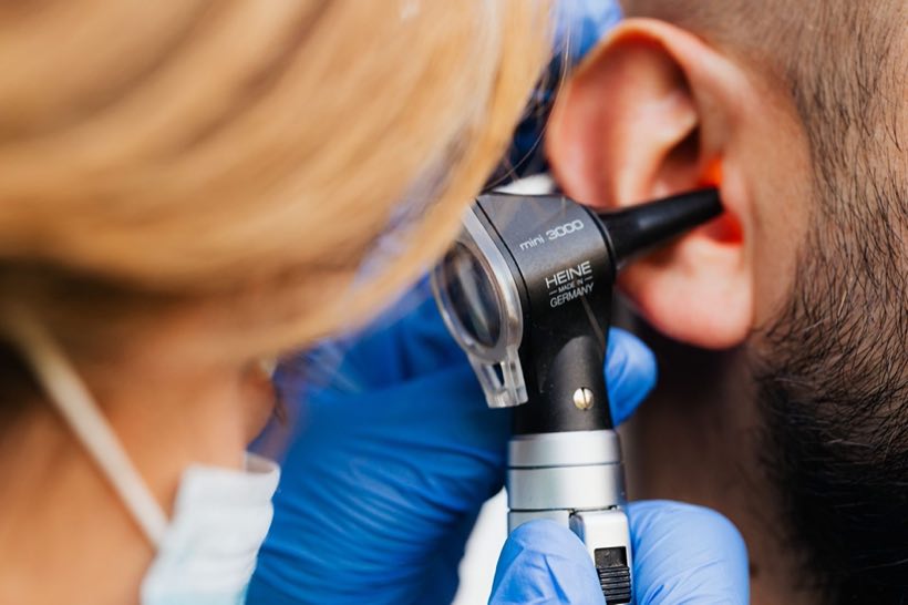 A medical professional examines a patient's ear using a Heine otoscope, highlighting healthcare quality