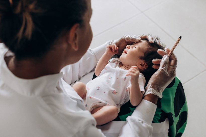 A medical professional examines a newborn baby indoors, highlighting healthcare and care