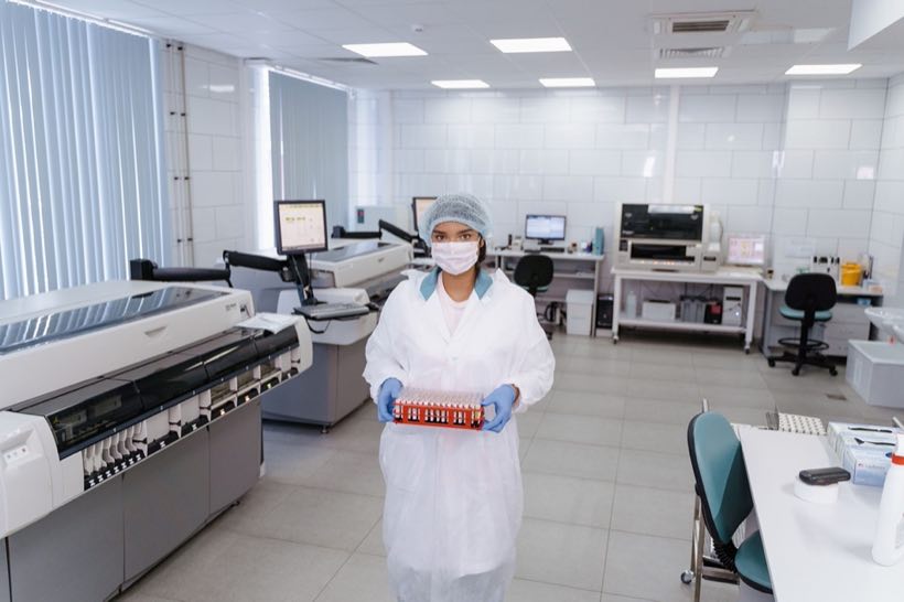 Scientist carrying a rack of samples through a genetics laboratory