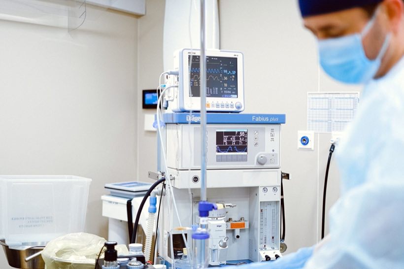Clinicians beside an anesthesia and ventilation workstation