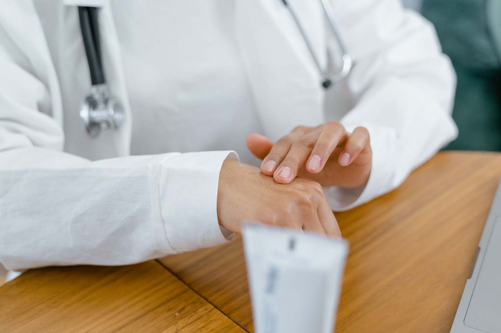 A healthcare professional in a white coat applying cream to a patient