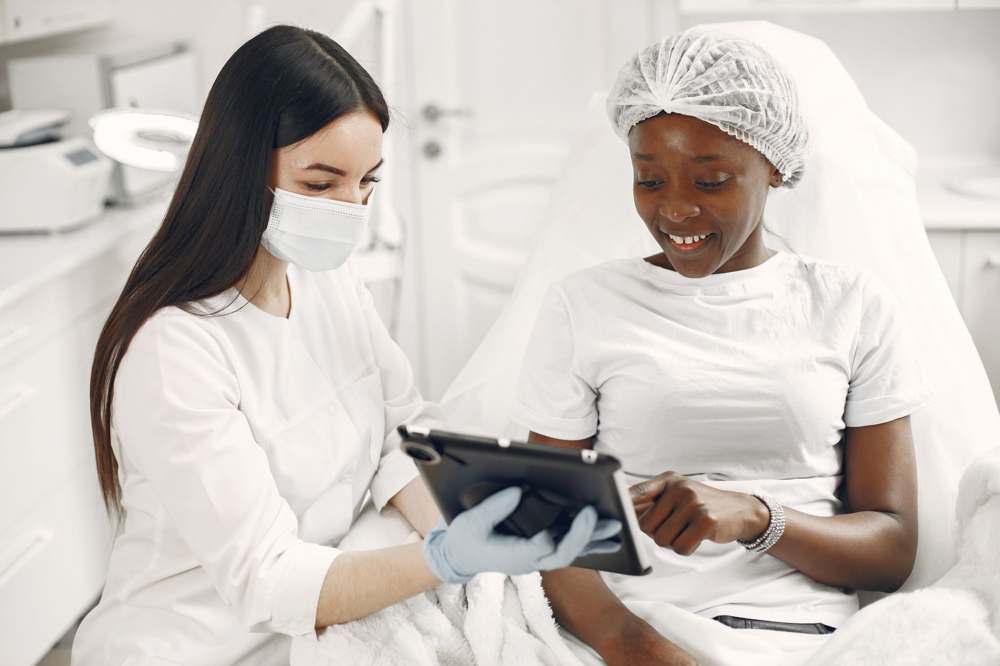 A dermatologist and patient reviewing information on a tablet