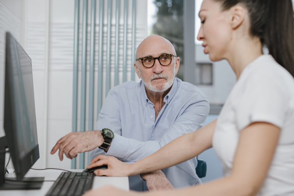 Elderly man receiving consultation from a medical practitioner in a modern indoor setting
