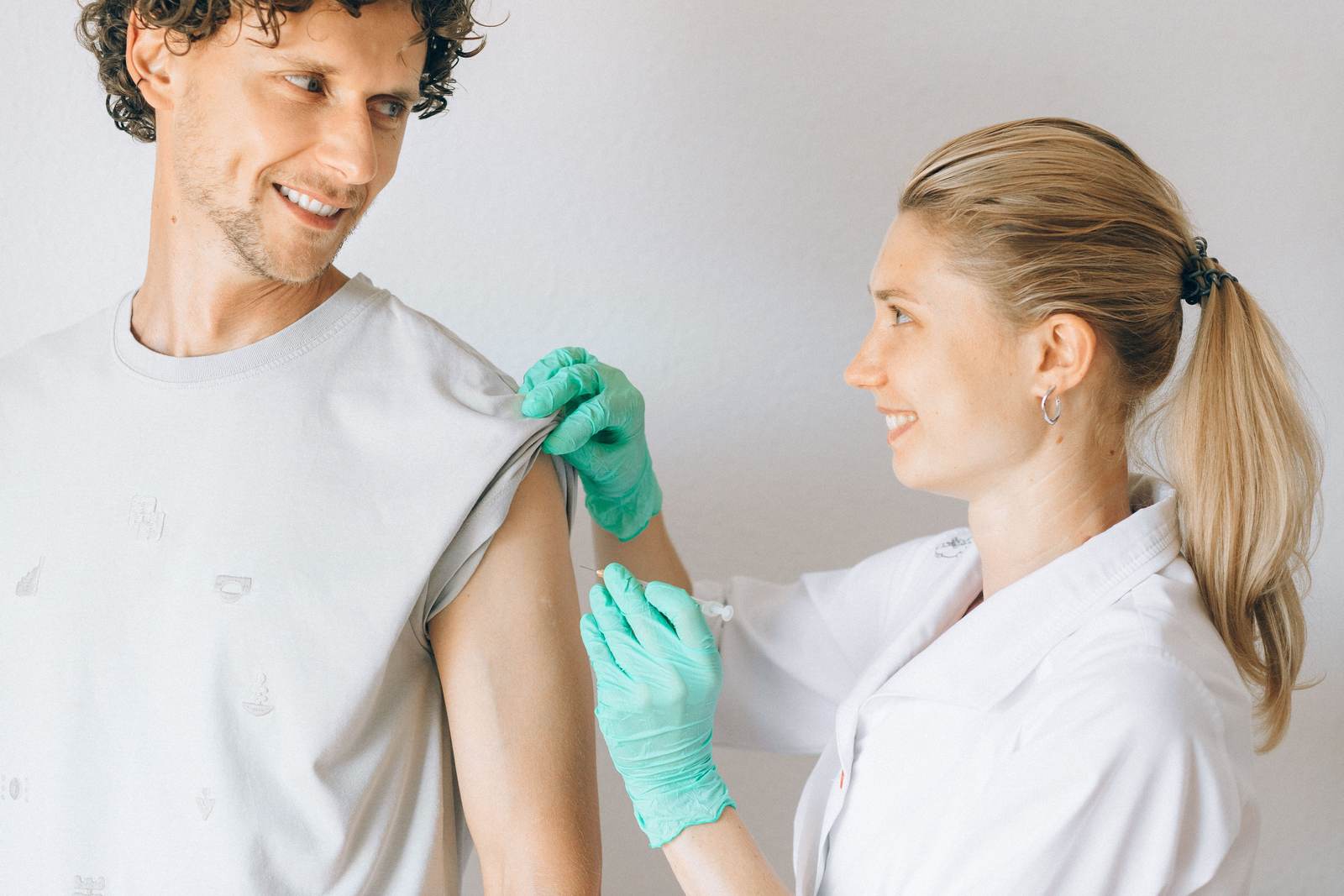 A nurse administering a vaccination to a smiling patient