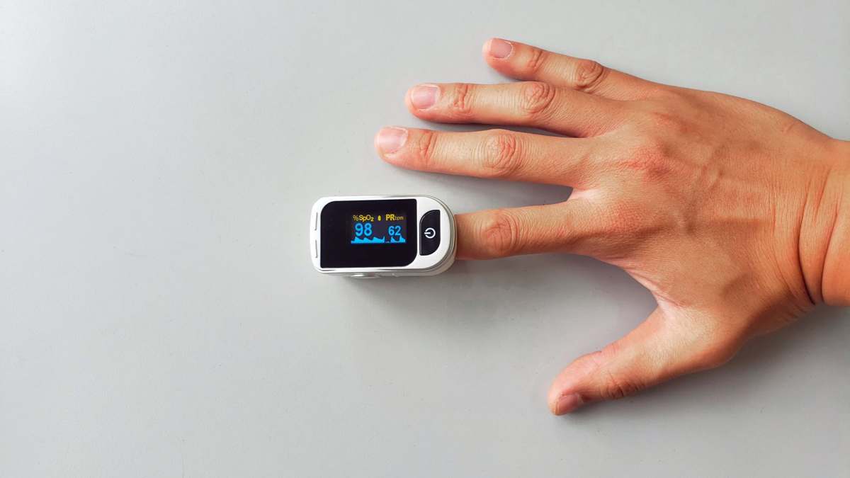 A close-up of a hand wearing a pulse oximeter