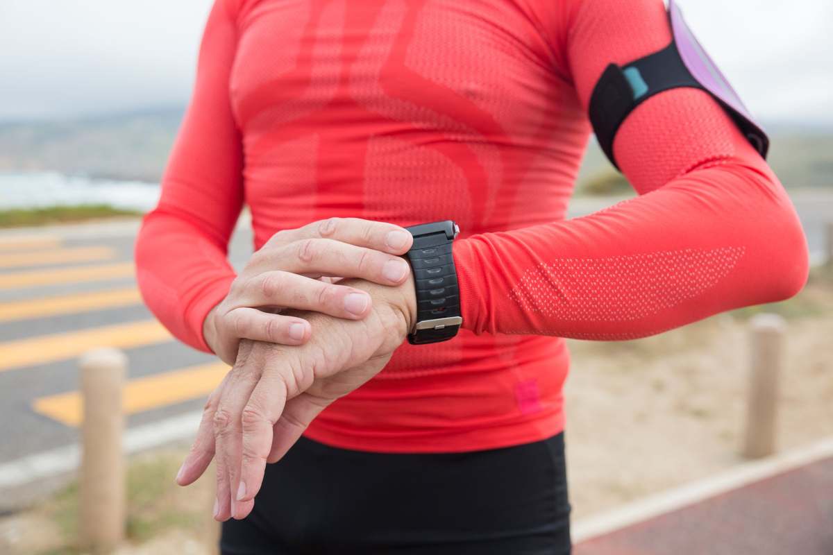 A person in activewear checking their wristwatch during exercise