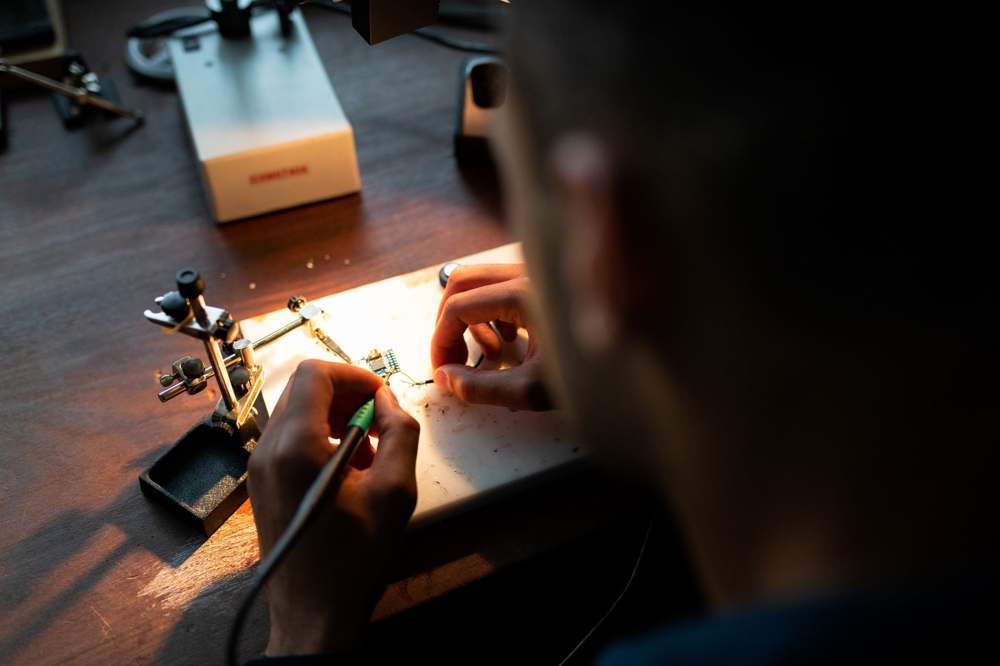 An engineer soldering a circuit board under bright light