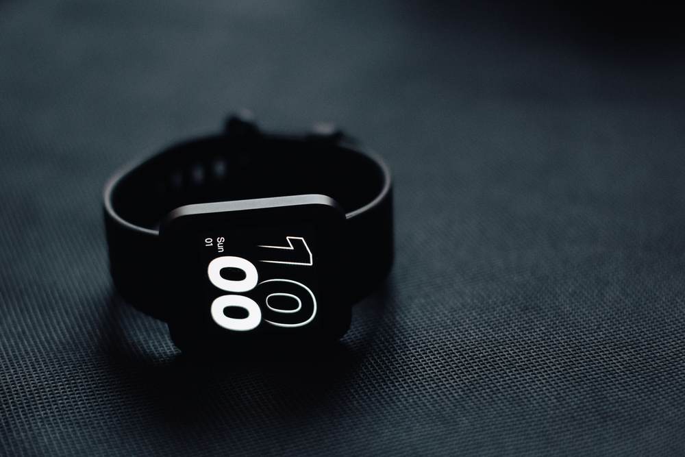 A modern smartwatch displaying time on a dark surface