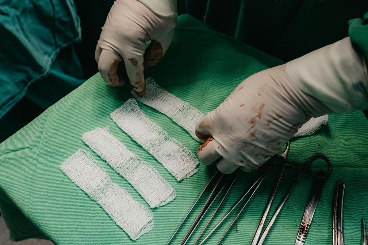 Surgeon's hands in gloves preparing bandages on a sterile field during surgery