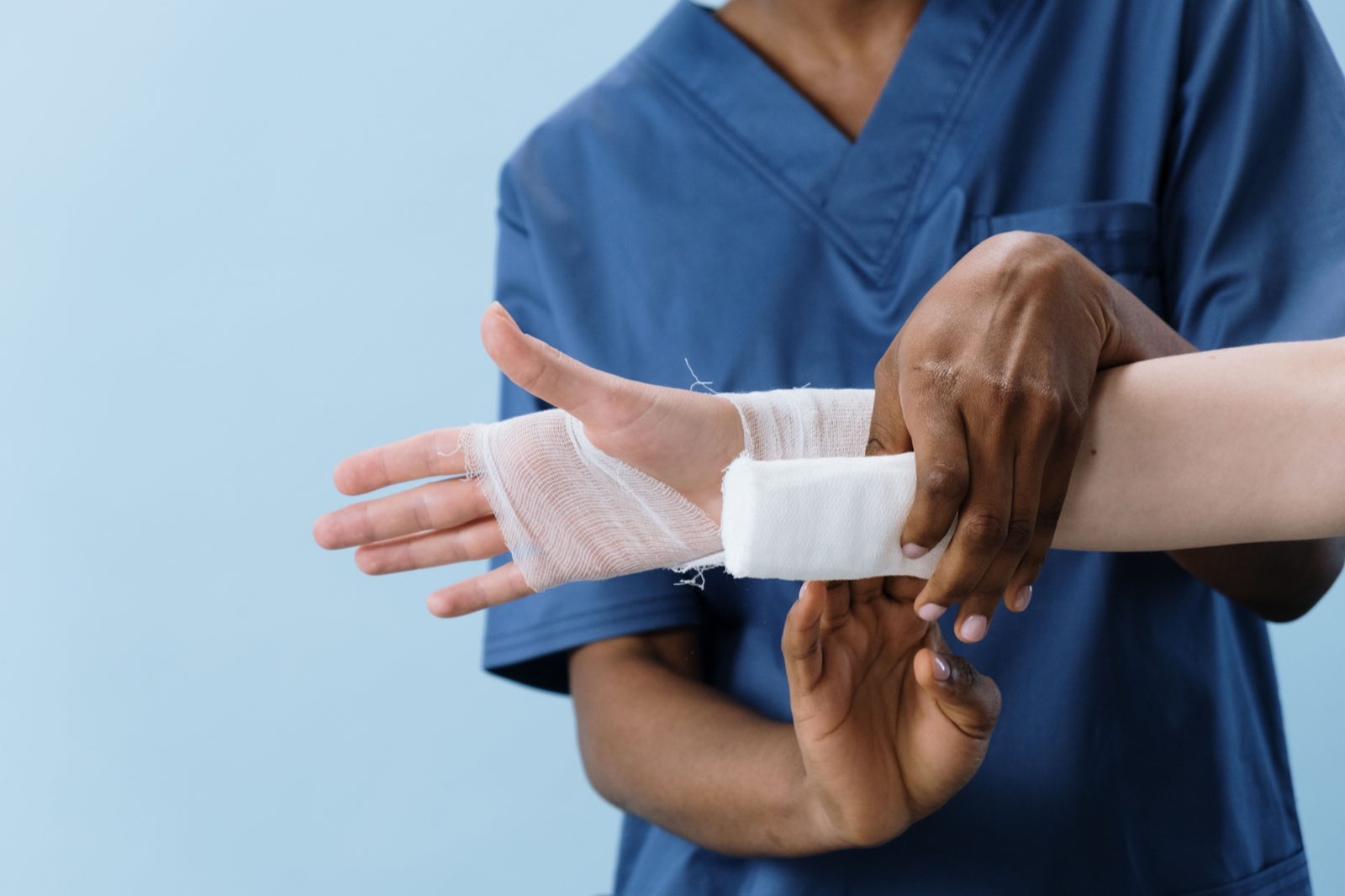 A medical professional carefully wrapping a bandage around an injured person's hand